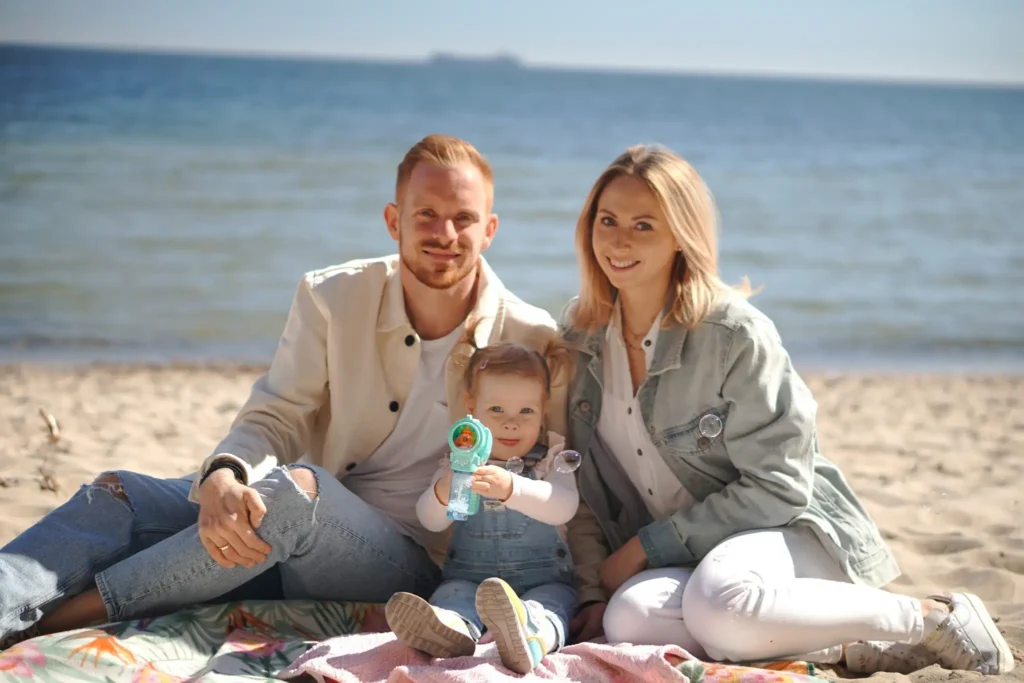 Młoda rodzina z dzieckiem siedząca na morskiej plaży.
