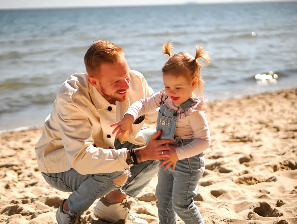 Ojciec bawiący się z córką na morskiej plaży.