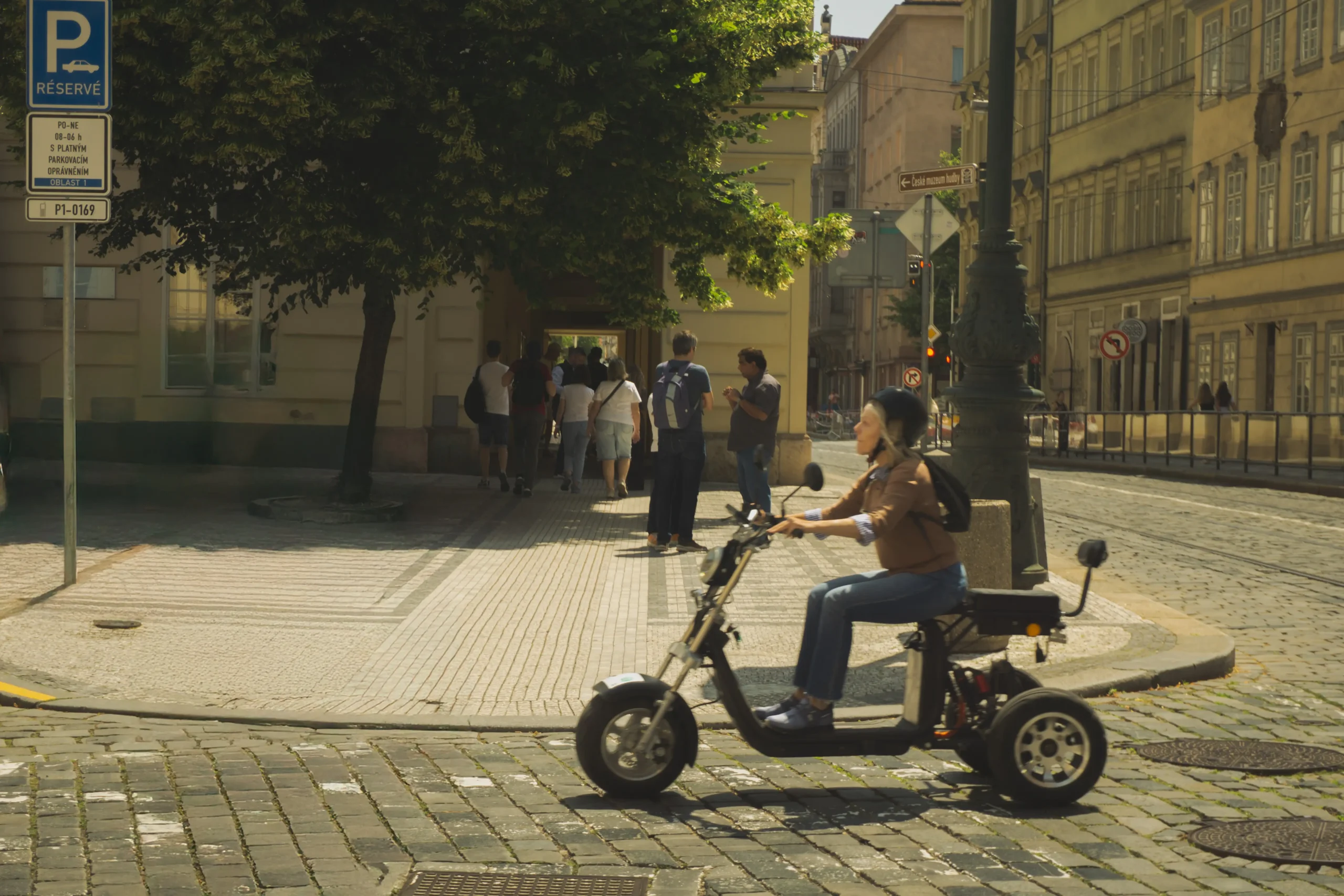 Kobieta w kasku przemierzająca miasto na oryginalnym pojeździe na wzór motocyklu.