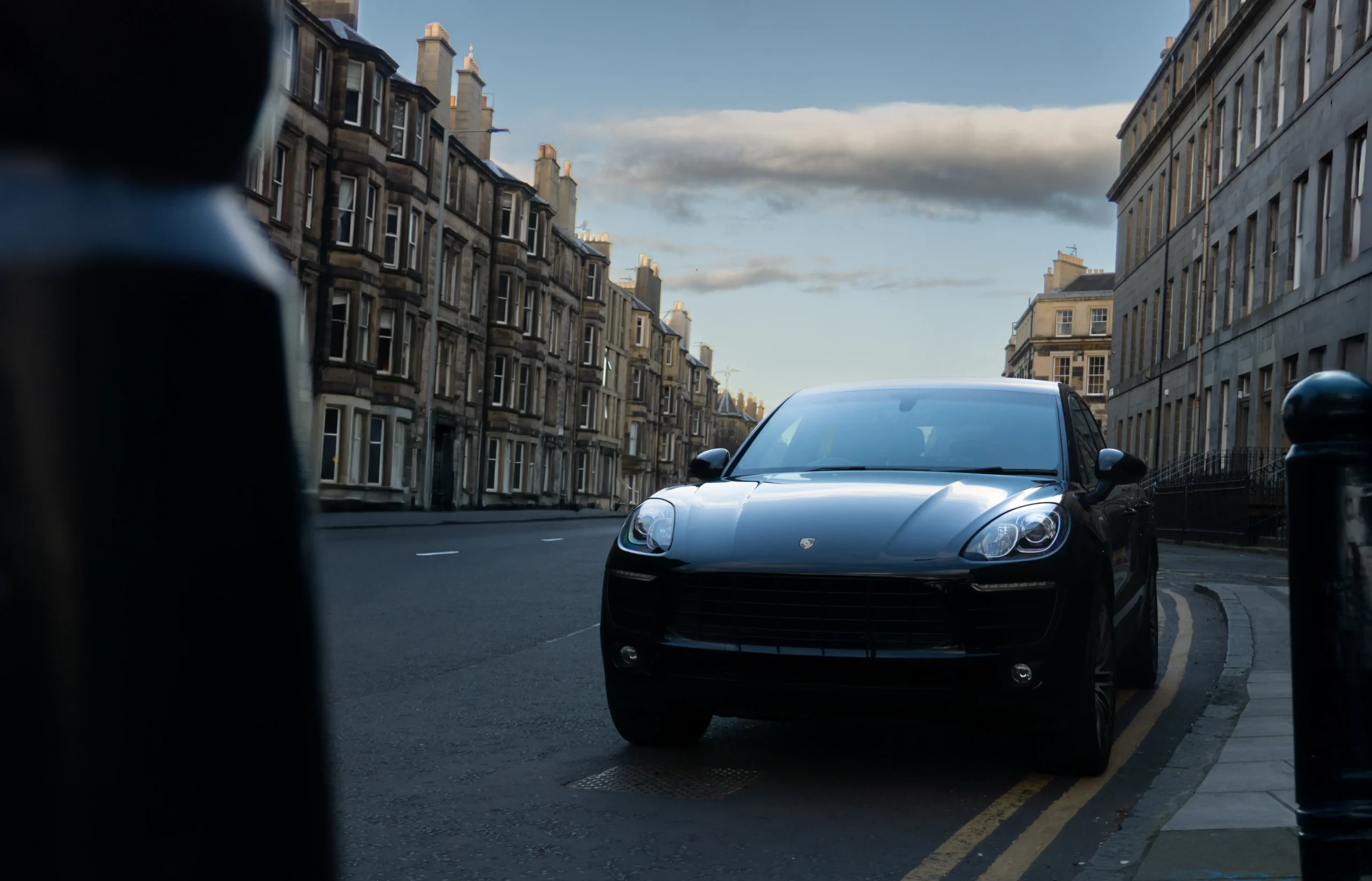 Czarne porsche stojące przy chodniku na tle miasta.