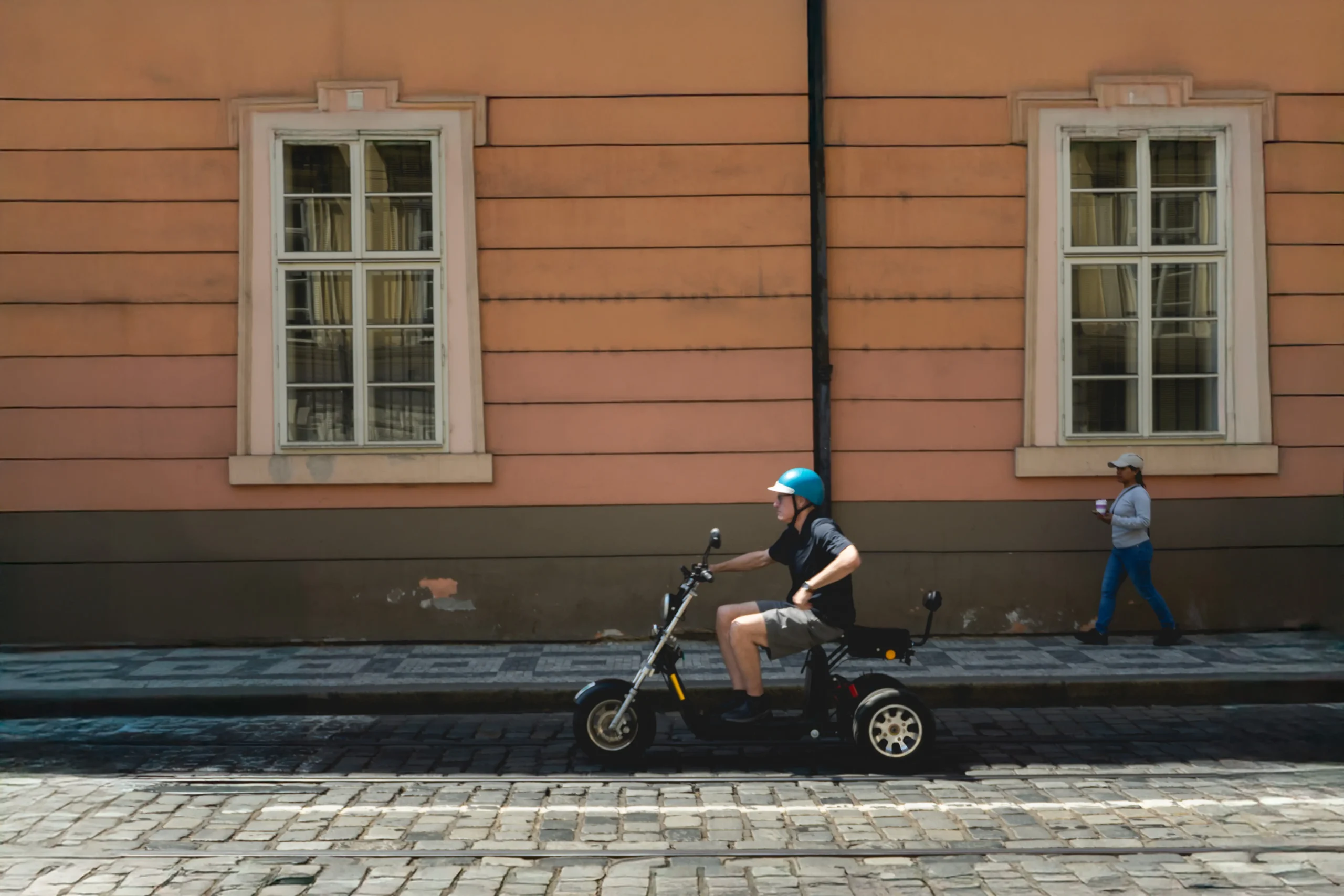 Mężczyzna w niebieskim kasku przemierzający miasto na oryginalnym pojeździe na wzór motocyklu.
